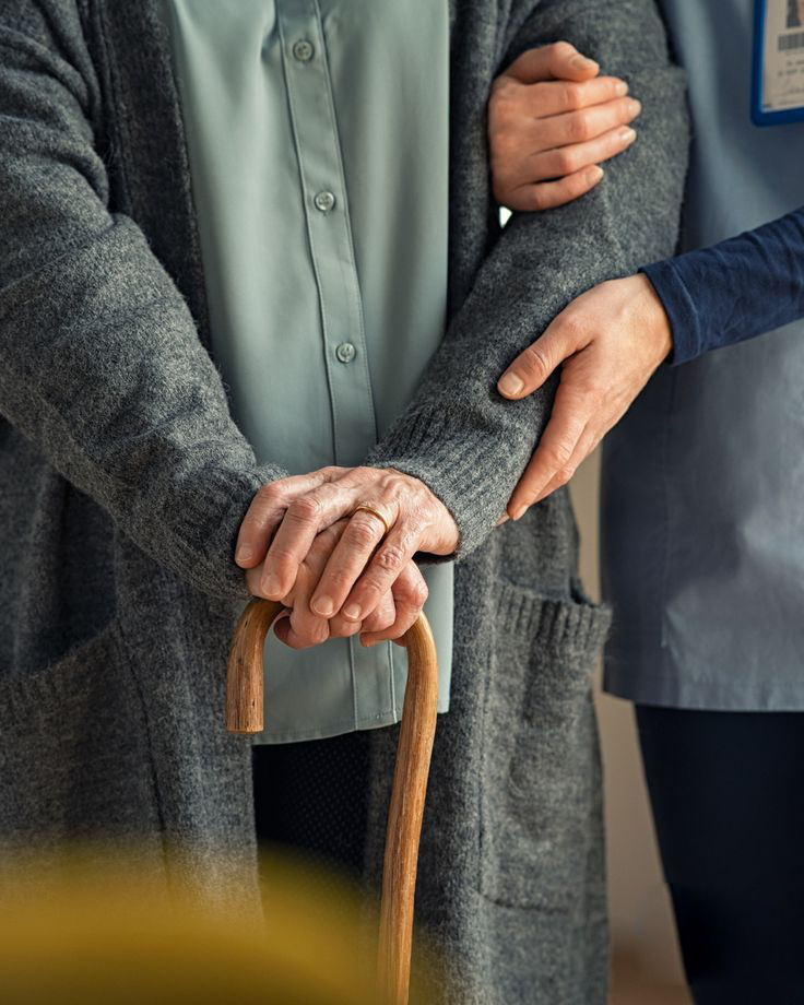 A care-giver holding the hand of an elderly patient